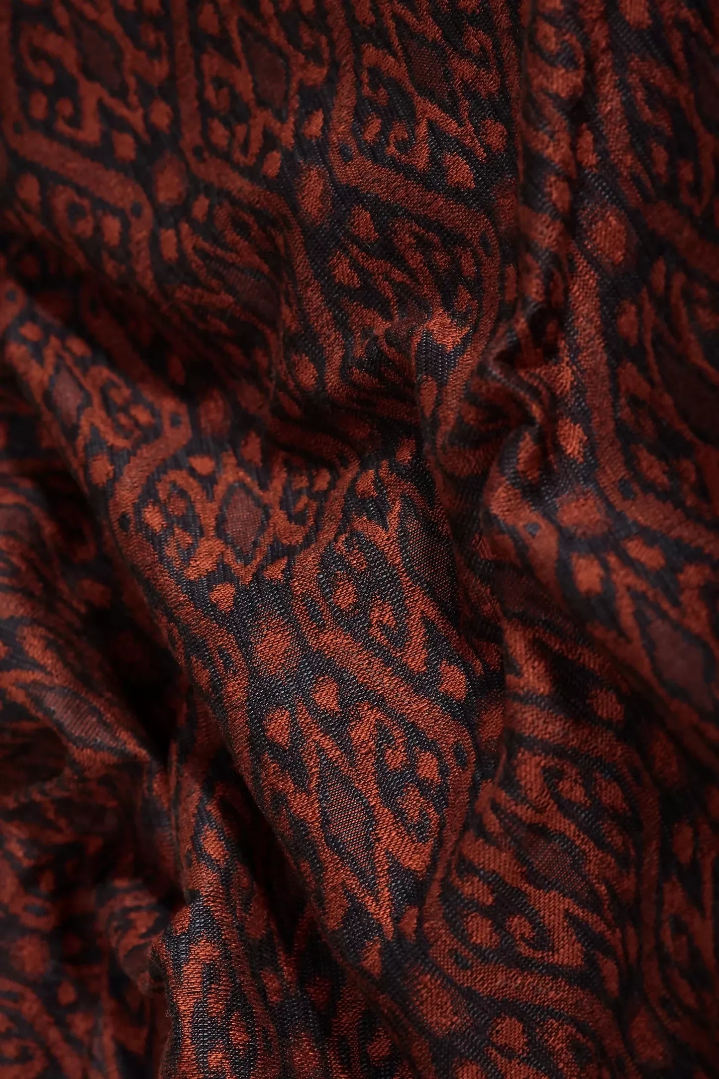 Close-up view of a woven ikat fabric in shades of dark navy and burgundy, displaying the intricate pattern and texture,  available  to buy on the-salon.com. SALON curates the finest , unique, handmade pieces from the interior industry's best makers and brands. Shop luxury furniture, lighting, rugs, art, antiques and vintage pieces and accessories from SALON interior designed rooms.