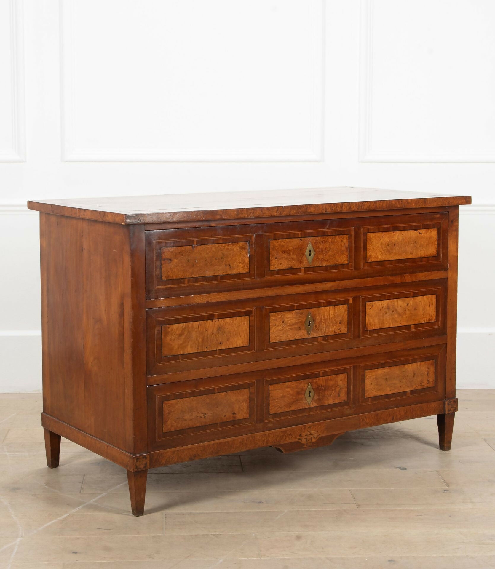 Wooden dresser with multiple drawers on a light wooden floor and white wall background,  available  to buy on the-salon.com. SALON curates the finest , unique, handmade pieces from the interior industry's best makers and brands. Shop luxury furniture, lighting, rugs, art, antiques and vintage pieces and accessories from SALON interior designed rooms.