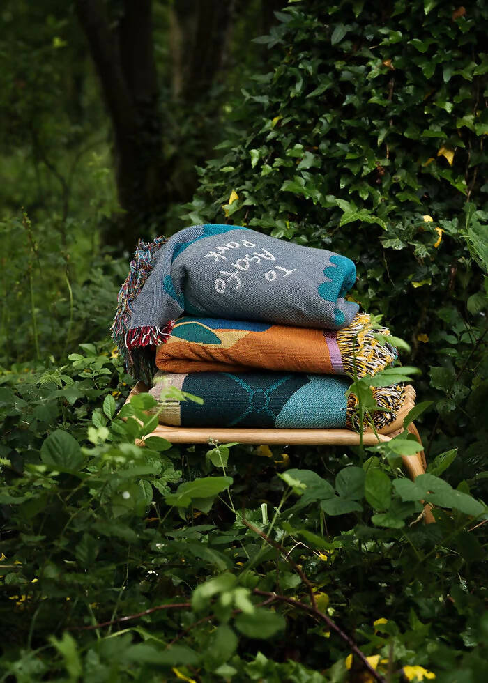 A colourful throw blanket featuring an illustration of a bird, an ostrich, and a jackal in a whimsical morning scene with the text 'Good morning' at the bottom,  available  to buy on the-salon.com. SALON curates the finest , unique, handmade pieces from the interior industry's best makers and brands. Shop luxury furniture, lighting, rugs, art, antiques and vintage pieces and accessories from SALON interior designed rooms.