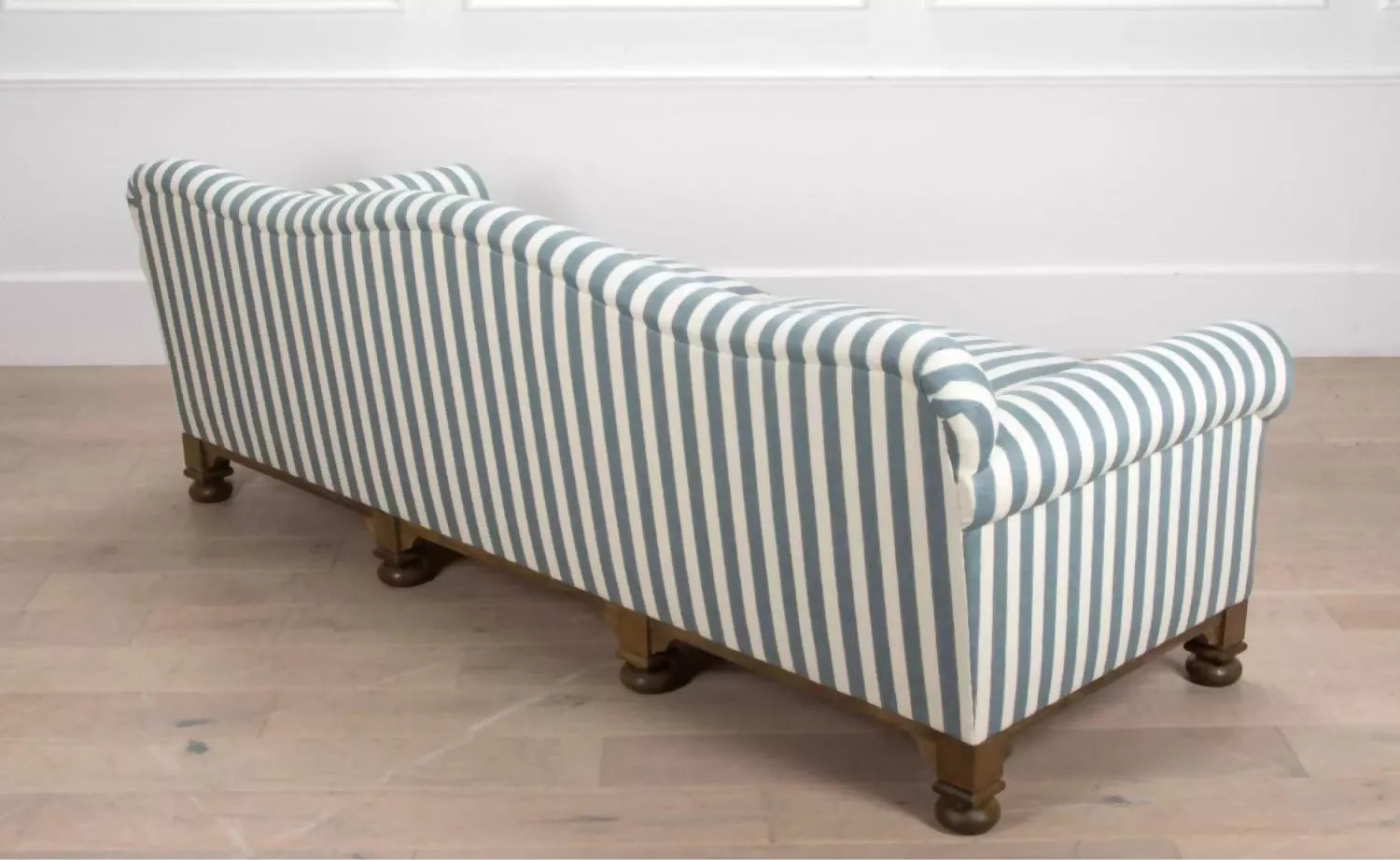 A blue and white striped camel back sofa with solid oak turned legs in a room with decorative items on top, available  to buy on the-salon.com. SALON curates the finest , unique, handmade pieces from the interior industry's best makers and brands. Shop luxury furniture, lighting, rugs, art, antiques and vintage pieces and accessories from SALON interior designed rooms.