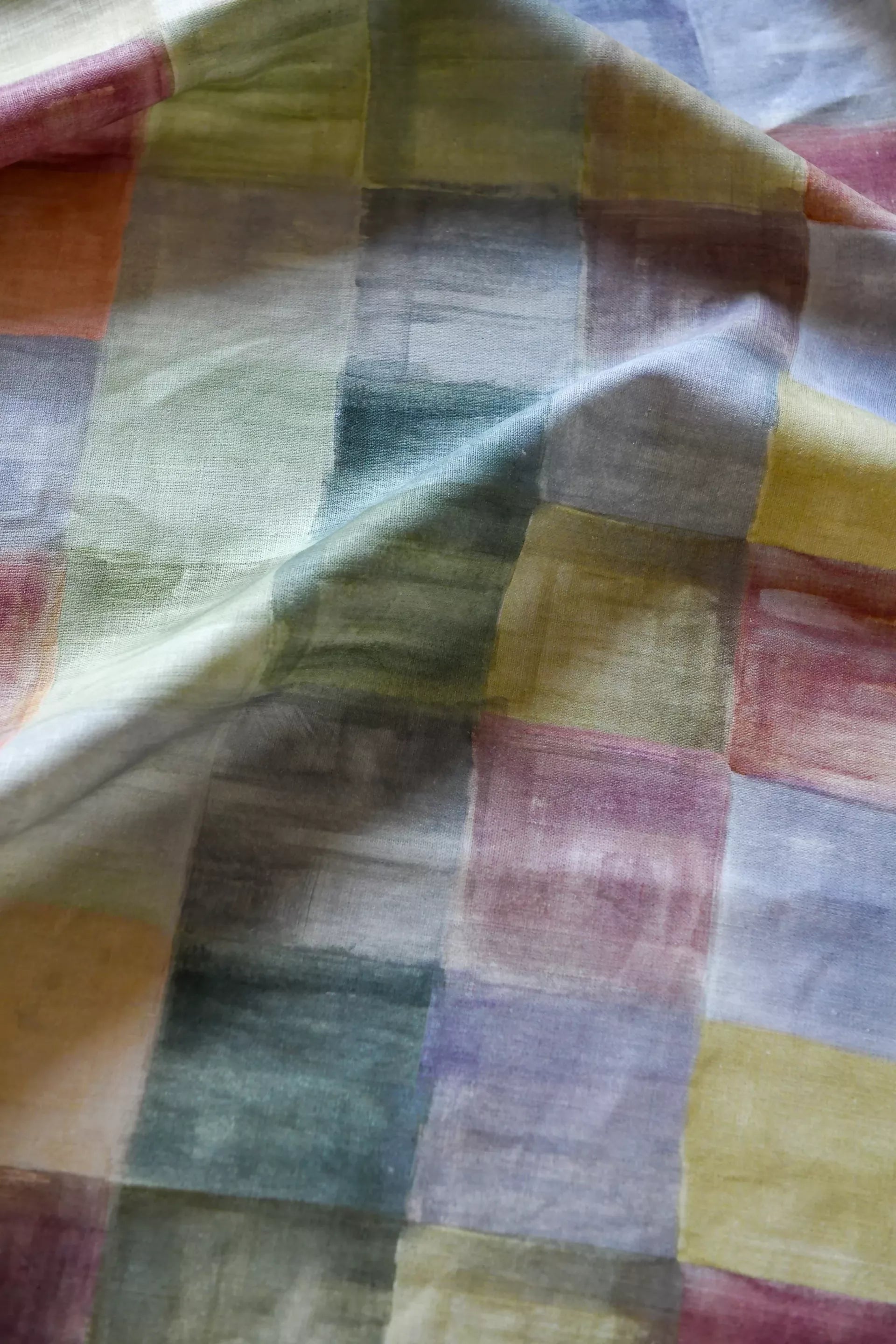 A close-up of a plaid fabric featuring a pattern of various solid colors, including blue, pink, green, and yellow,  available  to buy on the-salon.com. SALON curates the finest , unique, handmade pieces from the interior industry's best makers and brands. Shop luxury furniture, lighting, rugs, art, antiques and vintage pieces and accessories from SALON interior designed rooms.