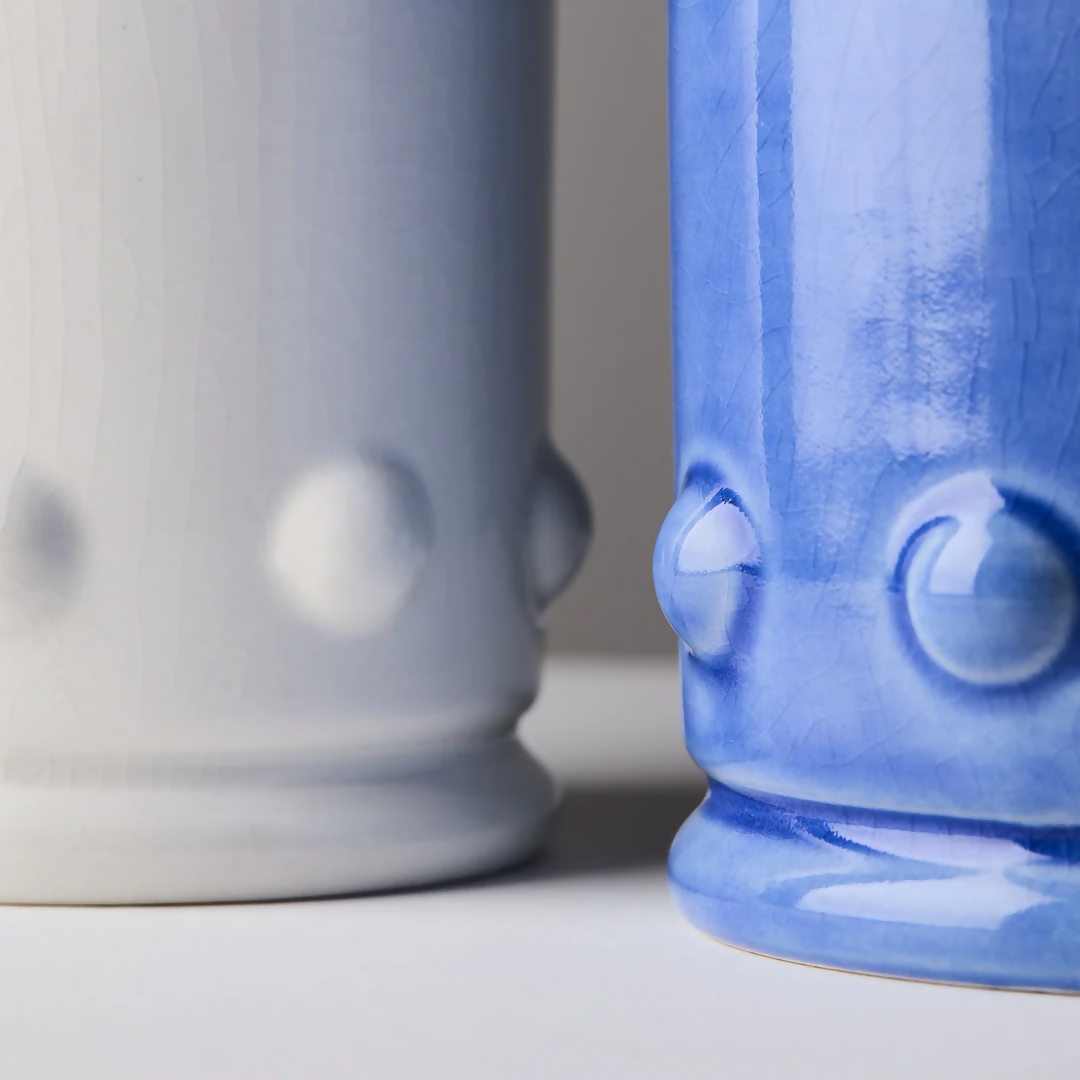 Blue and white ceramic candle vessels with a spherical detailing on the sides, with a close up on the detailing on the sides. The vessel is placed against a neutral background,  available  to buy on the-salon.com. SALON curates the finest , unique, handmade pieces from the interior industry's best makers and brands. Shop luxury furniture, lighting, rugs, art, antiques and vintage pieces and accessories from SALON interior designed rooms.