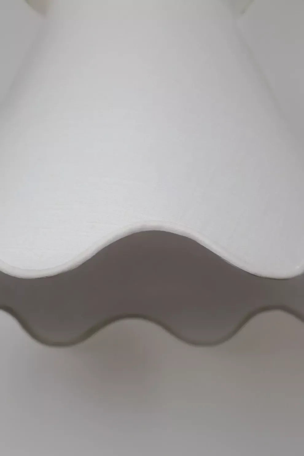 A pendant light with a pleated shade hanging over a dining table with a floral arrangement in the center, with curtains in the background, available  to buy on the-salon.com. SALON curates the finest , unique, handmade pieces from the interior industry's best makers and brands. Shop luxury furniture, lighting, rugs, art, antiques and vintage pieces and accessories from SALON interior designed rooms.