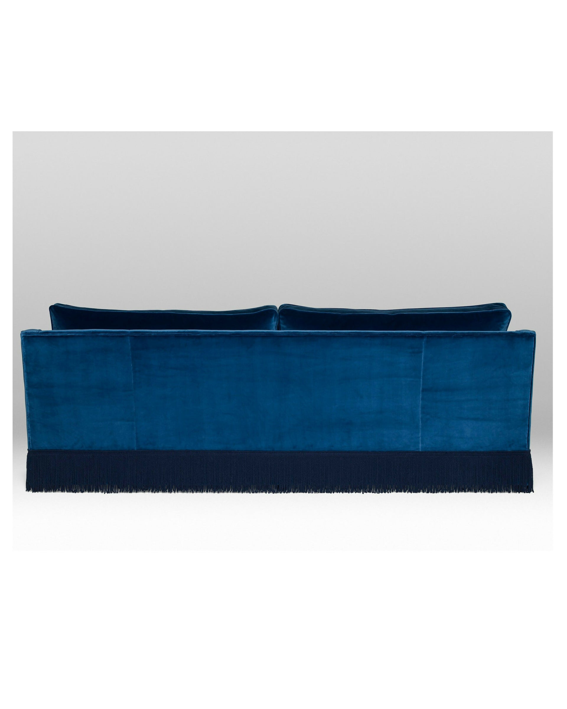 A blue velvet sofa with plush seats and a tasseled fringe, named 'Large Atlanta Sofa by Orior', available  to buy on the-salon.com. SALON curates the finest , unique, handmade pieces from the interior industry's best makers and brands. Shop luxury furniture, lighting, rugs, art, antiques and vintage pieces and accessories from SALON interior designed rooms.