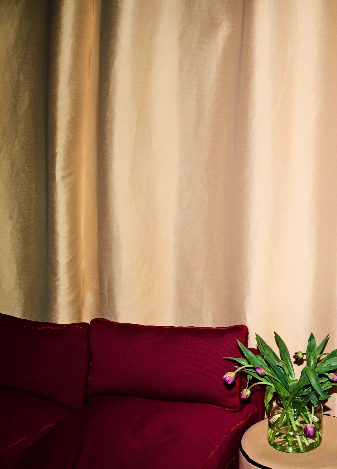 Close-up of a silk sateen fabric in a pale honey colour as curtains, showing its texture and sheen,  available  to buy on the-salon.com. SALON curates the finest , unique, handmade pieces from the interior industry's best makers and brands. Shop luxury furniture, lighting, rugs, art, antiques and vintage pieces and accessories from SALON interior designed rooms.