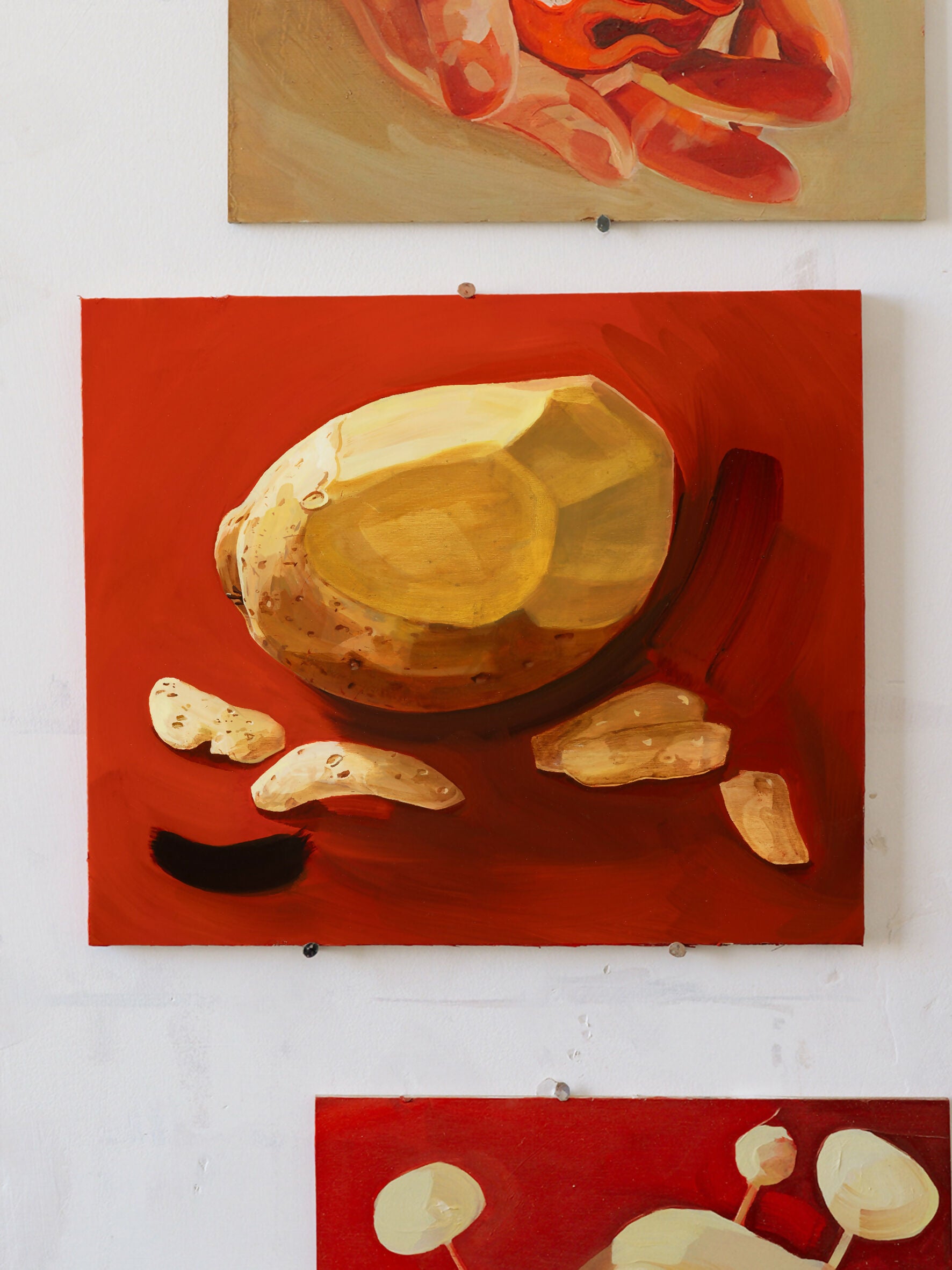 An oil painting by Sophie Glover featuring a peeled potato and slices on a red background, with a black element to the side,  available  to buy on the-salon.com. SALON curates the finest , unique, handmade pieces from the interior industry's best makers and brands. Shop luxury furniture, lighting, rugs, art, antiques and vintage pieces and accessories from SALON interior designed rooms.