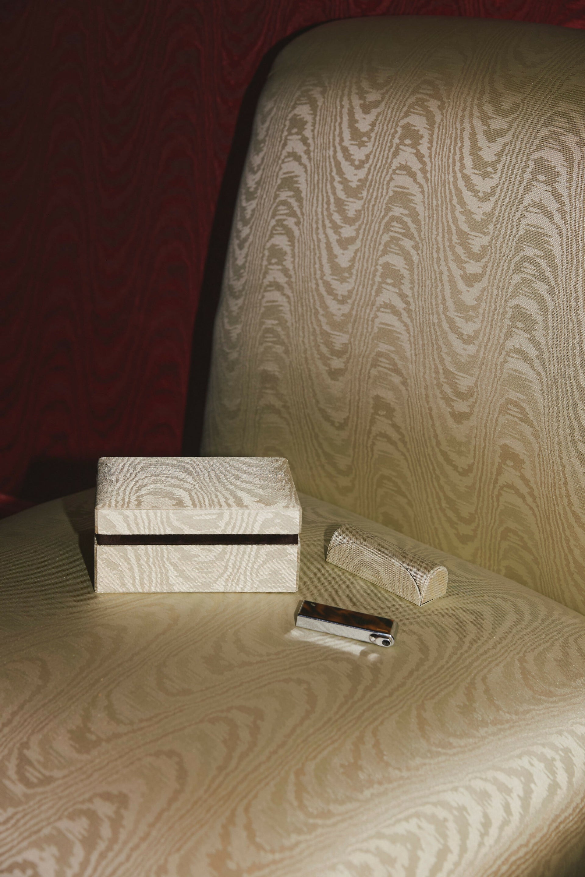 Wooden box and silver item on a textured surface with red background,  available  to buy on the-salon.com. SALON curates the finest , unique, handmade pieces from the interior industry's best makers and brands. Shop luxury furniture, lighting, rugs, art, antiques and vintage pieces and accessories from SALON interior designed rooms.