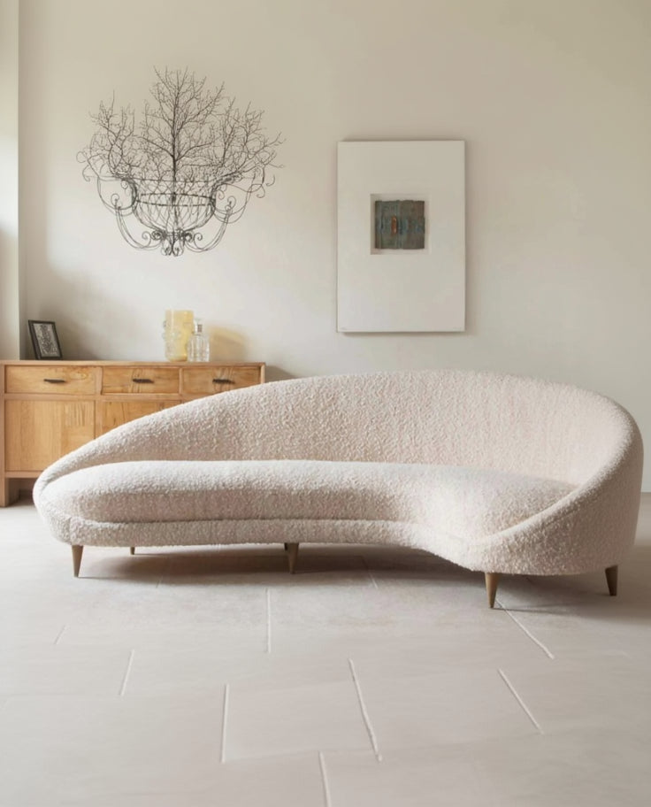 Modern beige sofa in a living room setting with a wooden sideboard and decorative items.