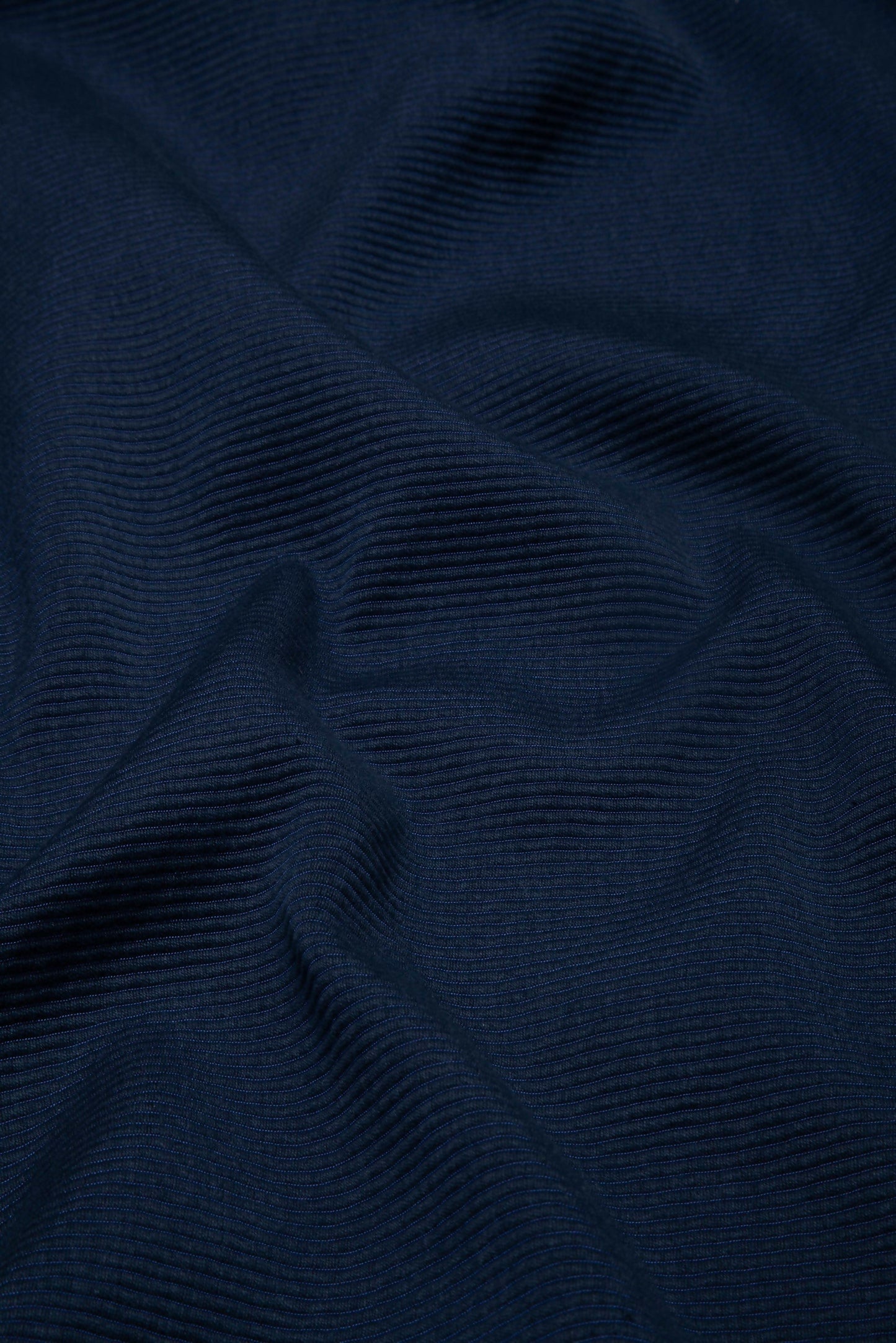 Close-up view of a navy blue fabric with a textured weave pattern,  available  to buy on the-salon.com. SALON curates the finest , unique, handmade pieces from the interior industry's best makers and brands. Shop luxury furniture, lighting, rugs, art, antiques and vintage pieces and accessories from SALON interior designed rooms.