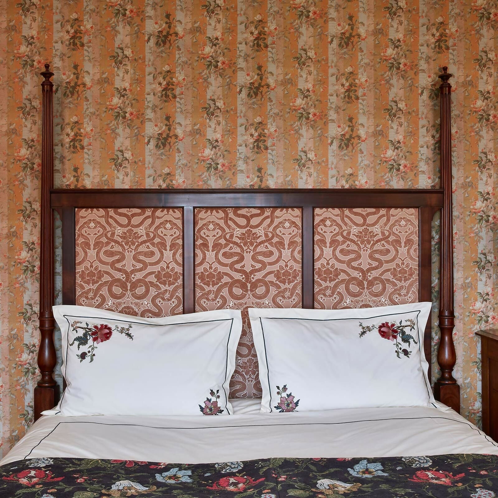 Bed with floral headboard and matching pillows against a floral wallpapered wall,  available  to buy on the-salon.com. SALON curates the finest , unique, handmade pieces from the interior industry's best makers and brands. Shop luxury furniture, lighting, rugs, art, antiques and vintage pieces and accessories from SALON interior designed rooms.