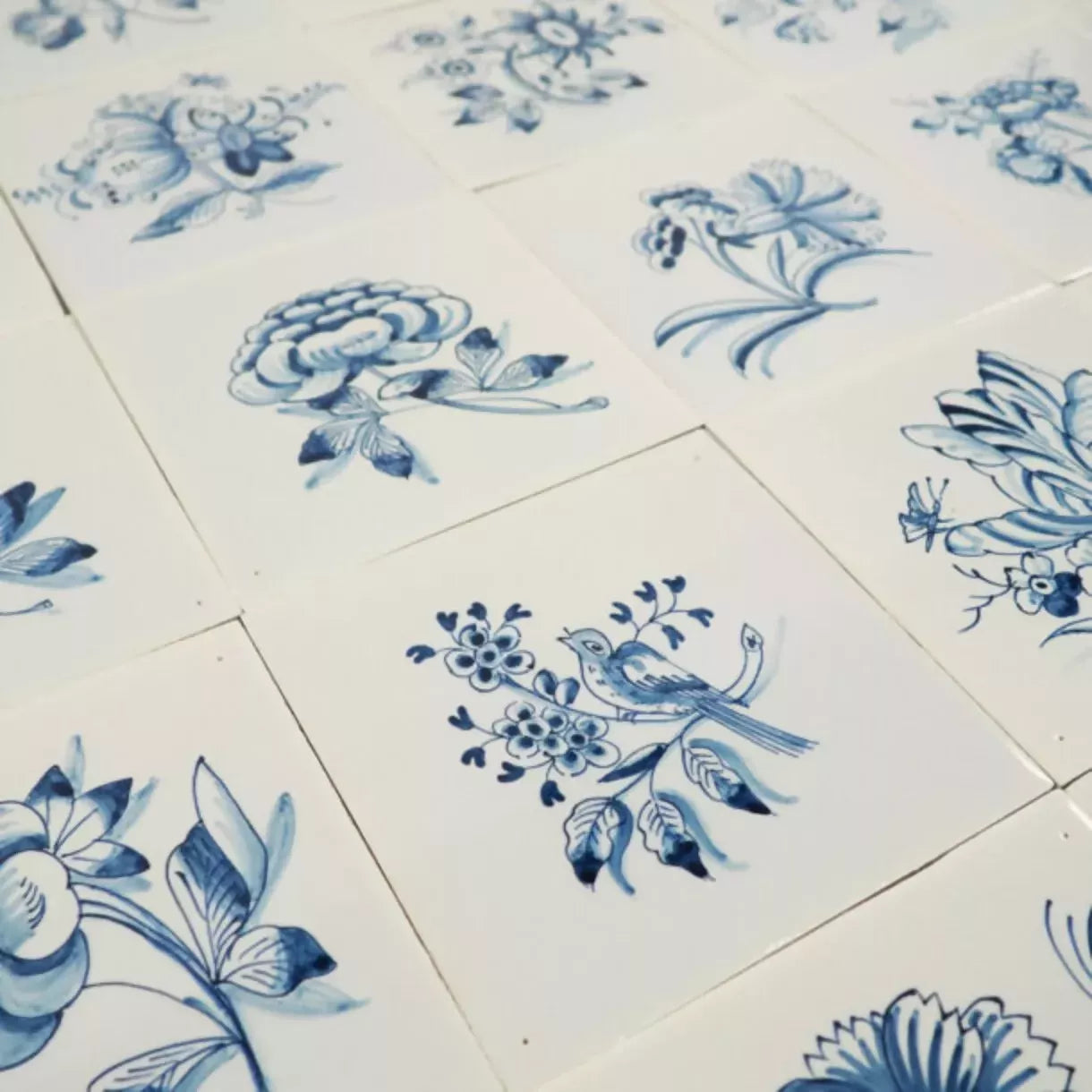 White tiles with blue floral and bird patterns,  available  to buy on the-salon.com. SALON curates the finest , unique, handmade pieces from the interior industry's best makers and brands. Shop luxury furniture, lighting, rugs, art, antiques and vintage pieces and accessories from SALON interior designed rooms.