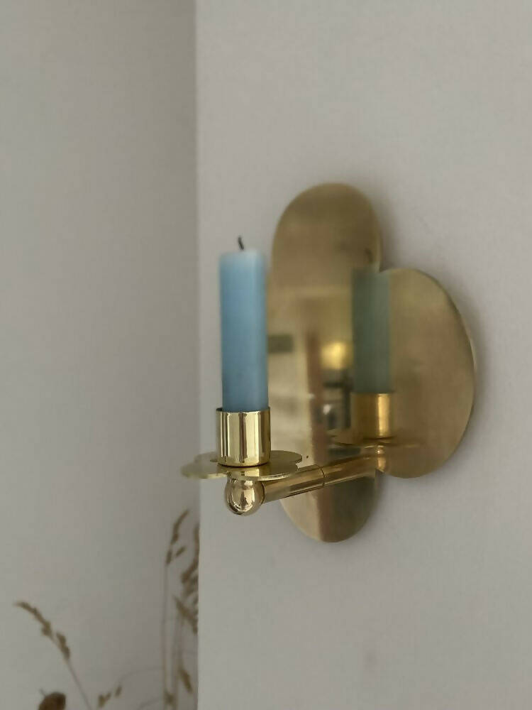 A solid brass wall-mounted candle sconce in the shape of a quatrefoil with a candle,  available  to buy on the-salon.com. SALON curates the finest , unique, handmade pieces from the interior industry's best makers and brands. Shop luxury furniture, lighting, rugs, art, antiques and vintage pieces and accessories from SALON interior designed rooms.