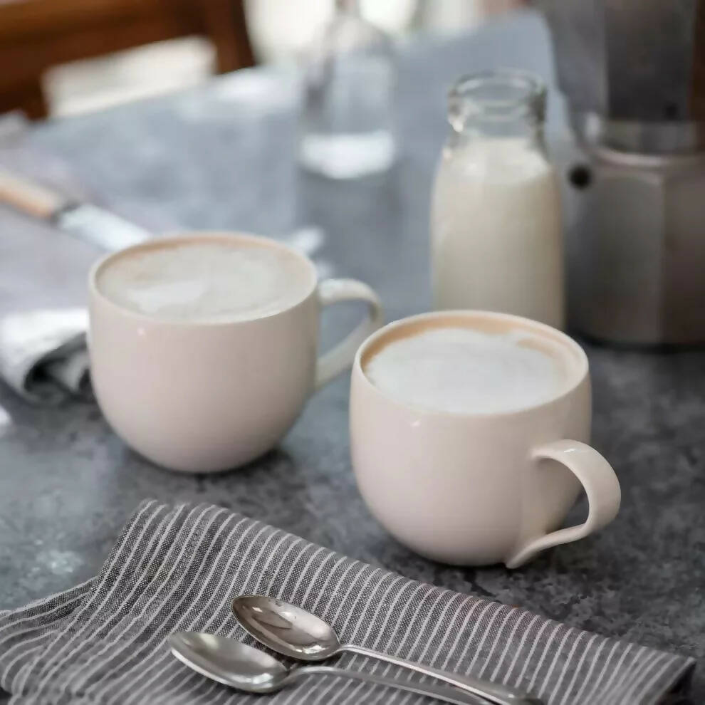 A simple, off-white porcelain mug with a handle, placed against a neutral background , available  to buy on the-salon.com. SALON curates the finest , unique, handmade pieces from the interior industry's best makers and brands. Shop luxury furniture, lighting, rugs, art, antiques and vintage pieces and accessories from SALON interior designed rooms.