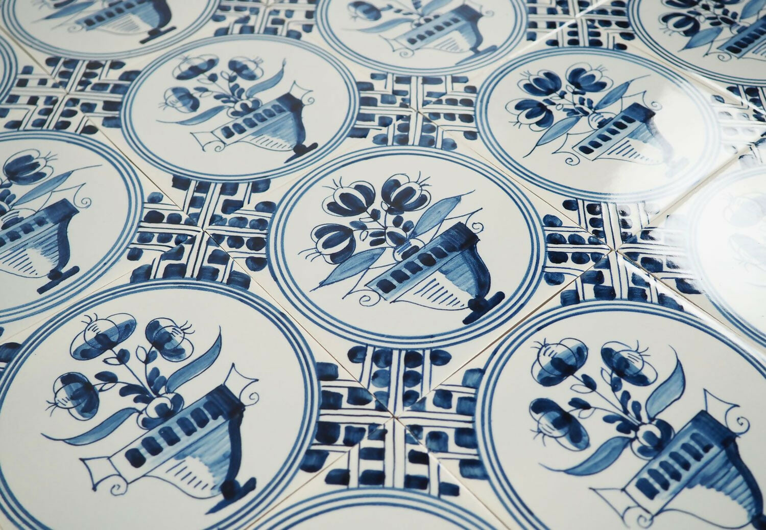 Close-up of blue and white ceramic tiles with floral and geometric patterns,  available  to buy on the-salon.com. SALON curates the finest , unique, handmade pieces from the interior industry's best makers and brands. Shop luxury furniture, lighting, rugs, art, antiques and vintage pieces and accessories from SALON interior designed rooms.