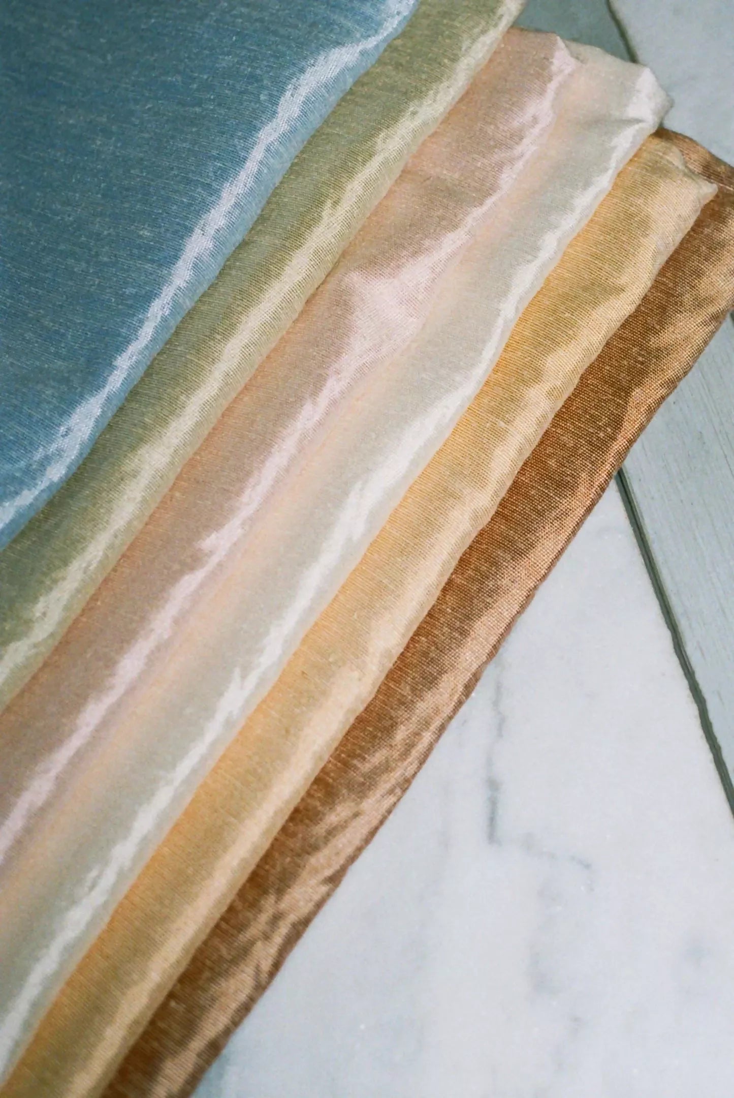 Silk sateen fabric in multiple colours stacked on each other, showing the texture and sheen,  available  to buy on the-salon.com. SALON curates the finest , unique, handmade pieces from the interior industry's best makers and brands. Shop luxury furniture, lighting, rugs, art, antiques and vintage pieces and accessories from SALON interior designed rooms.