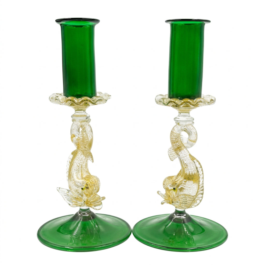 A pair of green and clear glass candlesticks with sculpted mermaid figures and circular green bases, photographed against a neutral light gray background.