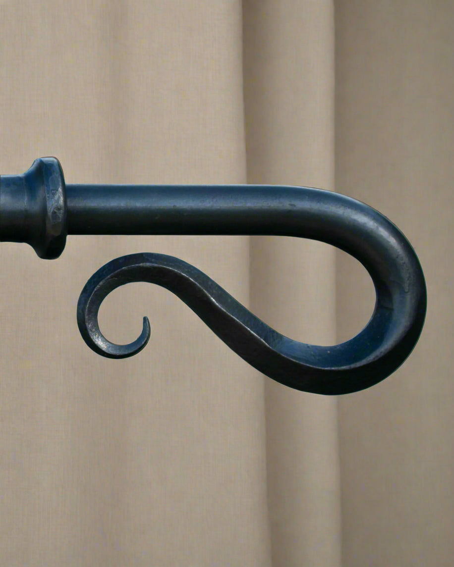 A close-up of a solid wrought iron curtain pole with a hand forged shepherd's crook finial, available  to buy on the-salon.com. SALON curates the finest , unique, handmade pieces from the interior industry's best makers and brands. Shop luxury furniture, lighting, rugs, art, antiques and vintage pieces and accessories from SALON interior designed room