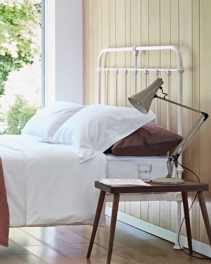 Bedroom with a bed, side tables, and a view of trees outside.