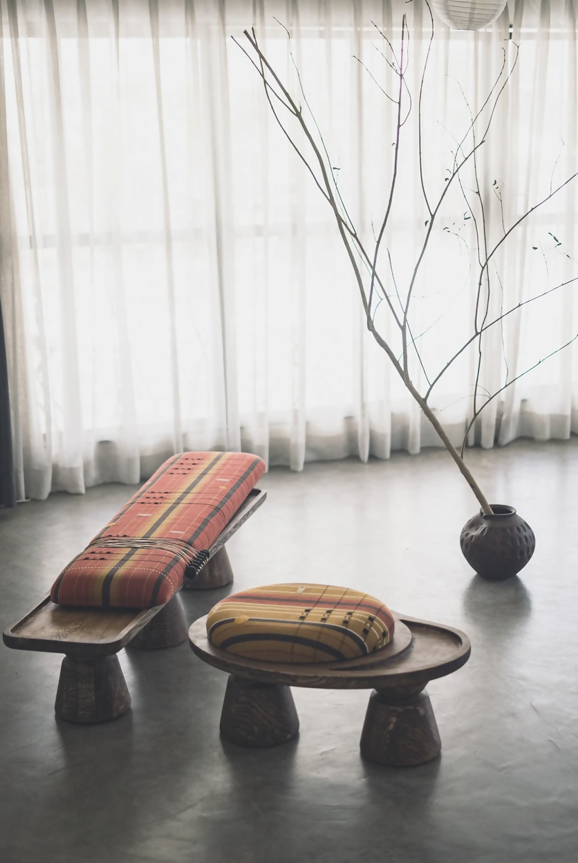 Two wooden stools with patterned cushions in a room with white curtains and a vase with branches,  available  to buy on the-salon.com. SALON curates the finest , unique, handmade pieces from the interior industry's best makers and brands. Shop luxury furniture, lighting, rugs, art, antiques and vintage pieces and accessories from SALON interior designed rooms.