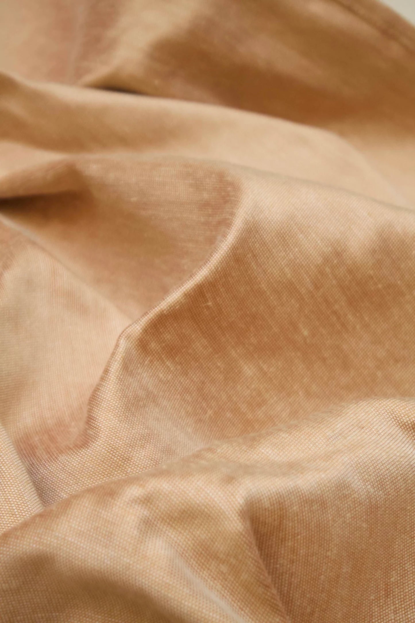 Close-up of a silk sateen fabric in a mottled red and orange color, with a slight sheen from the silk content,  available  to buy on the-salon.com. SALON curates the finest , unique, handmade pieces from the interior industry's best makers and brands. Shop luxury furniture, lighting, rugs, art, antiques and vintage pieces and accessories from SALON interior designed rooms.