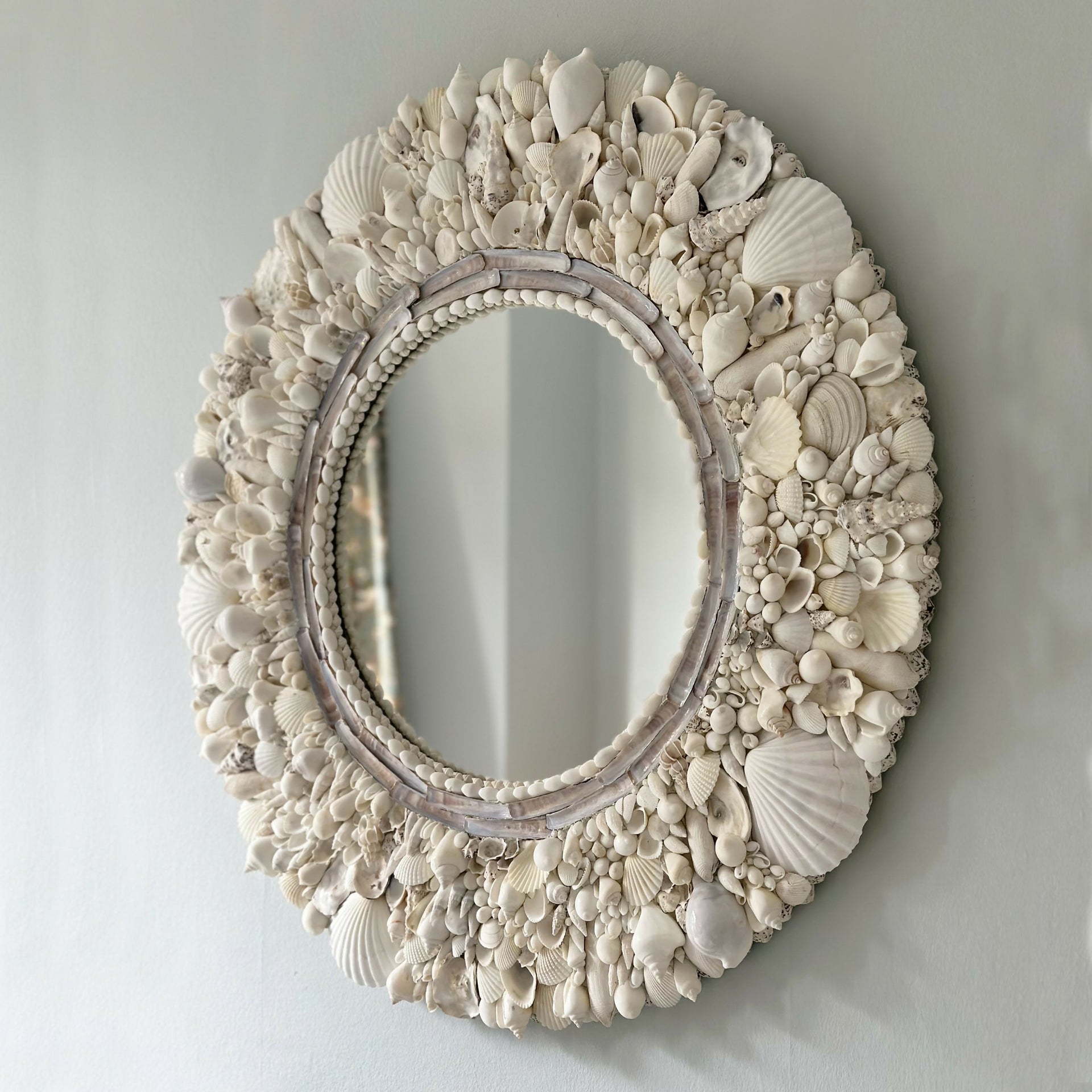 Decorative mirror with seashell frame on a light gray background,  available  to buy on the-salon.com. SALON curates the finest , unique, handmade pieces from the interior industry's best makers and brands. Shop luxury furniture, lighting, rugs, art, antiques and vintage pieces and accessories from SALON interior designed rooms.