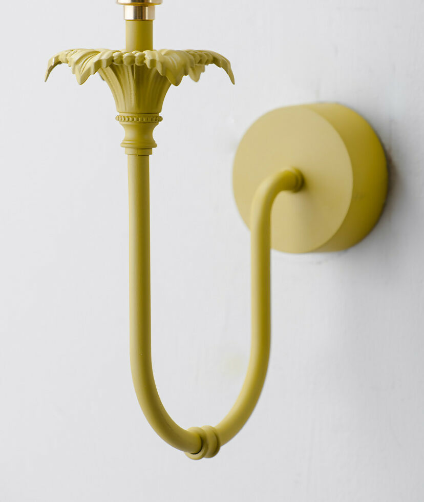 A wall-mounted light fixture with a yellow-colored metal arm and a white, solid-patterned lampshade,  available  to buy on the-salon.com. SALON curates the finest , unique, handmade pieces from the interior industry's best makers and brands. Shop luxury furniture, lighting, rugs, art, antiques and vintage pieces and accessories from SALON interior designed rooms.