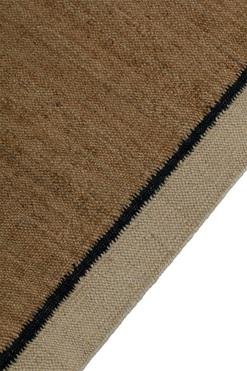 Close-up view of a hand-woven dhurrie rug with a plain texture and a visible border,  available  to buy on the-salon.com. SALON curates the finest , unique, handmade pieces from the interior industry's best makers and brands. Shop luxury furniture, lighting, rugs, art, antiques and vintage pieces and accessories from SALON interior designed rooms.