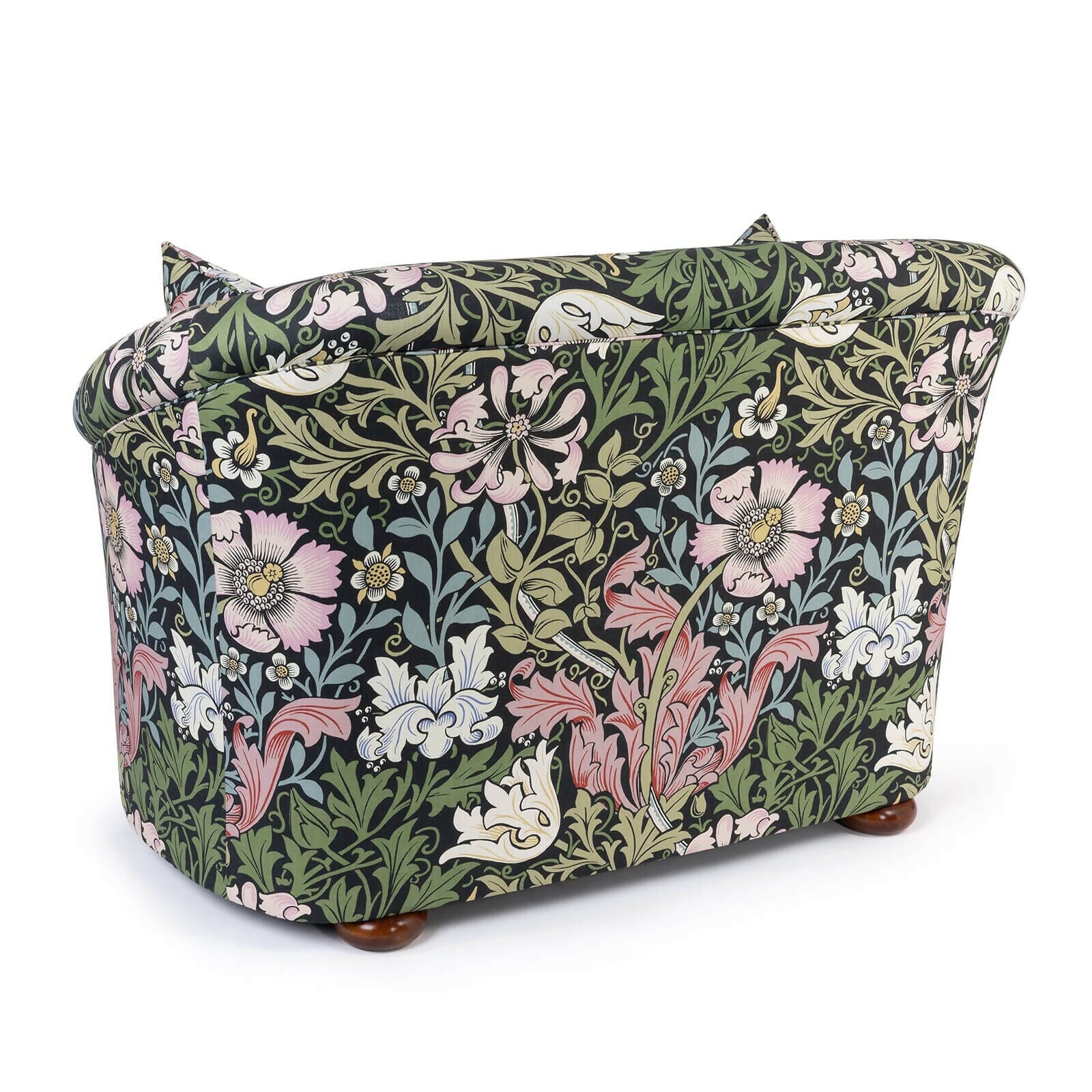 A Vesper Loveseat with a floral pattern in a mix of green, pink, and other colors on a black background, featuring sloping arms and a continuous curved backrest, with a pair of matching scatter cushions,  available  to buy on the-salon.com. SALON curates the finest , unique, handmade pieces from the interior industry's best makers and brands. Shop luxury furniture, lighting, rugs, art, antiques and vintage pieces and accessories from SALON interior designed rooms.