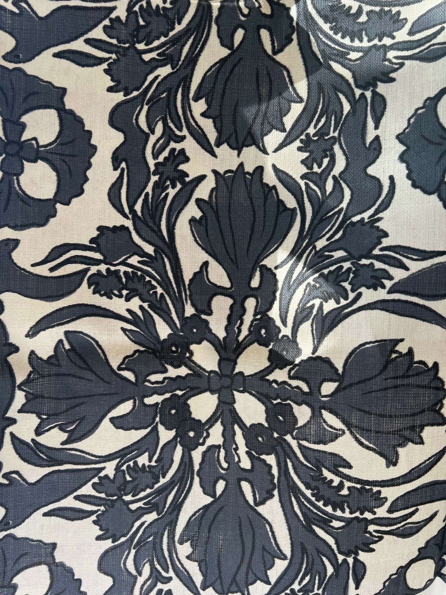 A close-up view of a vintage scarf fabric featuring a detailed and ornate floral pattern in shades of black and gray on a beige background,  available  to buy on the-salon.com. SALON curates the finest , unique, handmade pieces from the interior industry's best makers and brands. Shop luxury furniture, lighting, rugs, art, antiques and vintage pieces and accessories from SALON interior designed rooms.