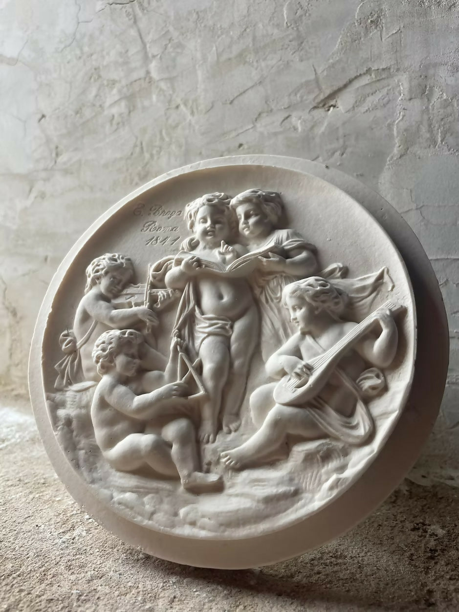 A plaster cast roundel featuring five putti performing music,  available  to buy on the-salon.com. SALON curates the finest , unique, handmade pieces from the interior industry's best makers and brands. Shop luxury furniture, lighting, rugs, art, antiques and vintage pieces and accessories from SALON interior designed rooms.
