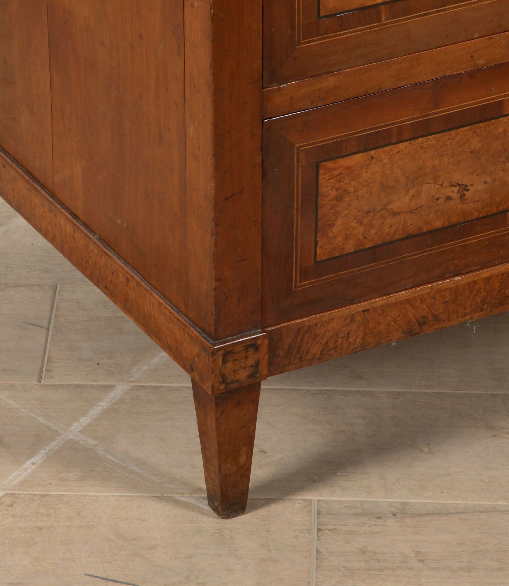 Close-up of a wooden cabinet corner on a tiled floor,  available  to buy on the-salon.com. SALON curates the finest , unique, handmade pieces from the interior industry's best makers and brands. Shop luxury furniture, lighting, rugs, art, antiques and vintage pieces and accessories from SALON interior designed rooms.