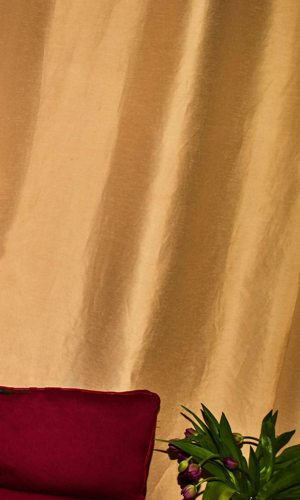 Close-up of a silk sateen fabric in a pale honey colour as curtains, showing its texture and sheen,  available  to buy on the-salon.com. SALON curates the finest , unique, handmade pieces from the interior industry's best makers and brands. Shop luxury furniture, lighting, rugs, art, antiques and vintage pieces and accessories from SALON interior designed rooms.