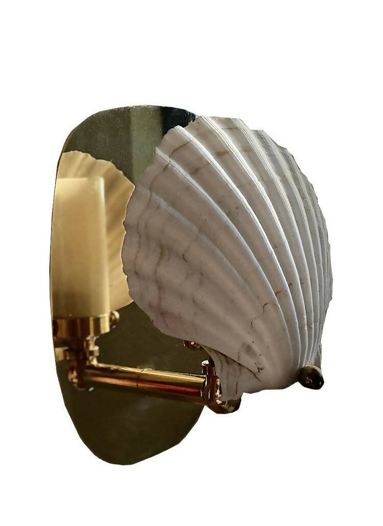 A wall light fixture with a chalky white scallop shell finish mounted on a polished brass backplate,  available  to buy on the-salon.com. SALON curates the finest , unique, handmade pieces from the interior industry's best makers and brands. Shop luxury furniture, lighting, rugs, art, antiques and vintage pieces and accessories from SALON interior designed rooms.