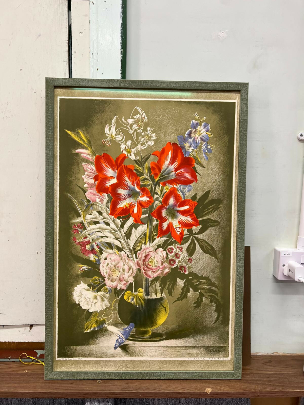 Framed botanical illustration of flowers on a wooden surface.