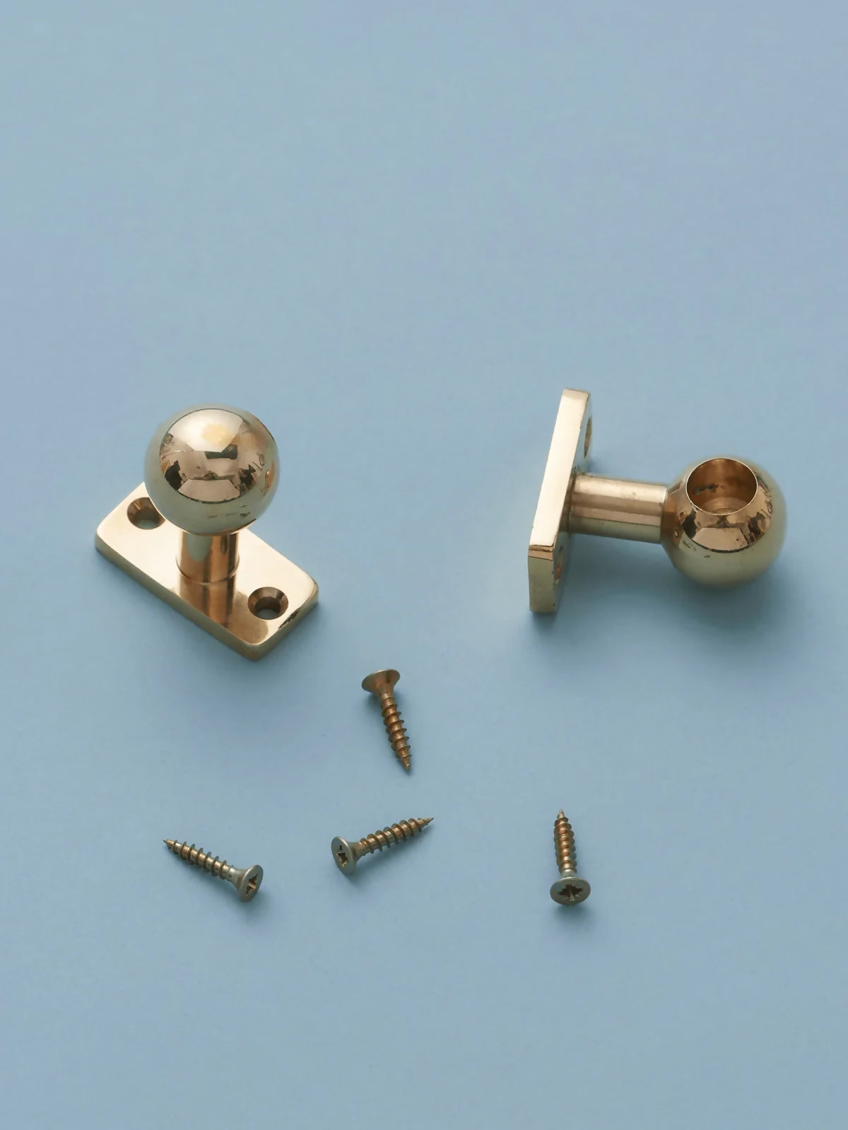 Gold door knobs with screws on a light blue background,  available  to buy on the-salon.com. SALON curates the finest , unique, handmade pieces from the interior industry's best makers and brands. Shop luxury furniture, lighting, rugs, art, antiques and vintage pieces and accessories from SALON interior designed rooms.