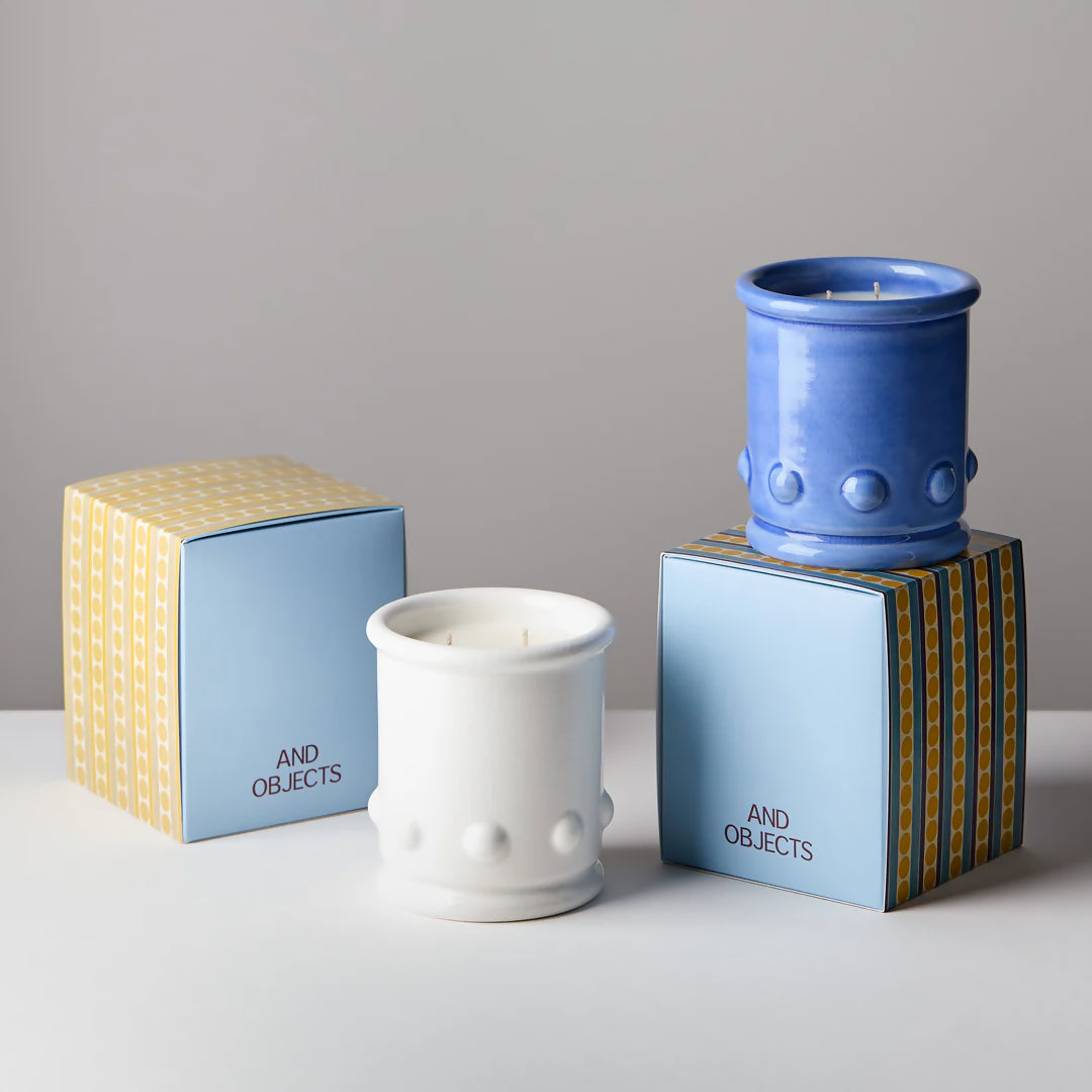 Blue and white ceramic candle vessels with spherical detailing on the sides, with a candle visible at the top. The vessel is placed against a neutral background,  available  to buy on the-salon.com. SALON curates the finest , unique, handmade pieces from the interior industry's best makers and brands. Shop luxury furniture, lighting, rugs, art, antiques and vintage pieces and accessories from SALON interior designed rooms.