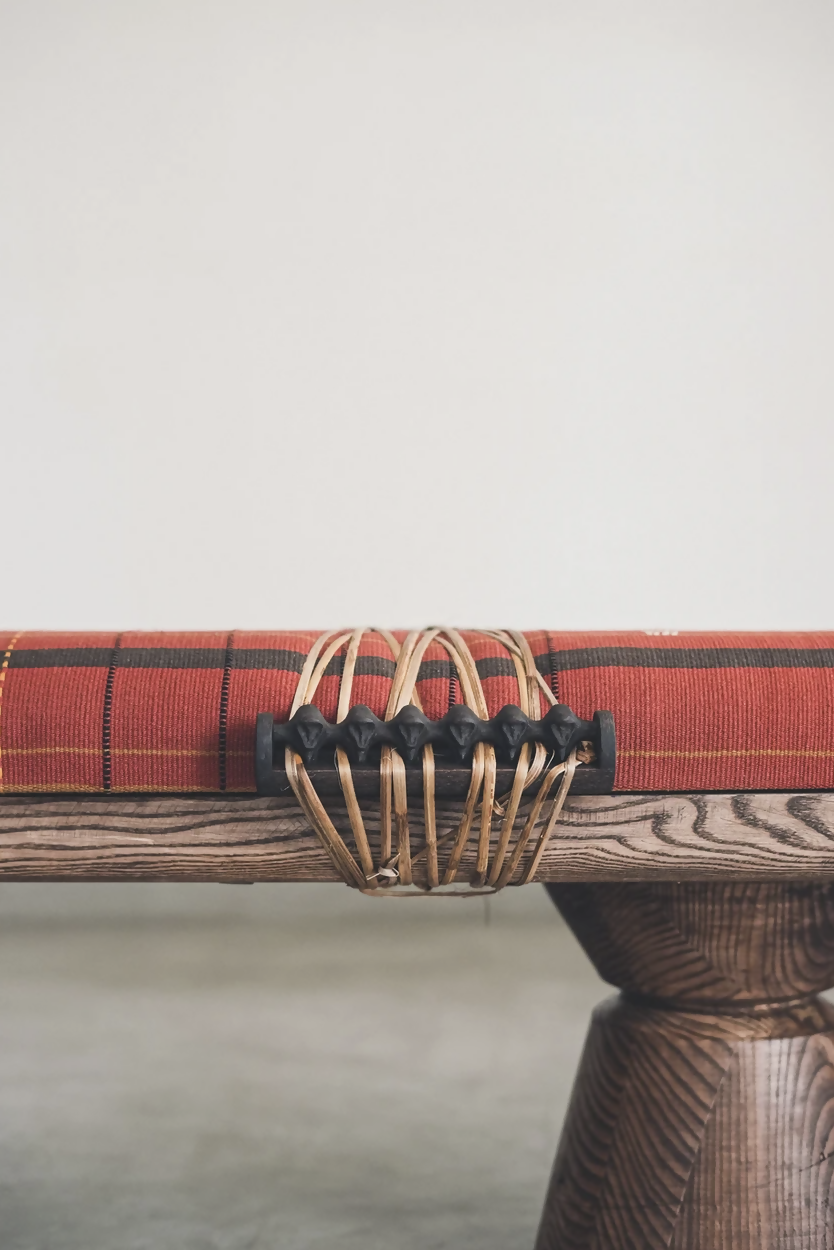 A close up of the wood woven onto the wooden table with a red tartan tablecloth and decorative metal holder on a neutral background,  available  to buy on the-salon.com. SALON curates the finest , unique, handmade pieces from the interior industry's best makers and brands. Shop luxury furniture, lighting, rugs, art, antiques and vintage pieces and accessories from SALON interior designed rooms.