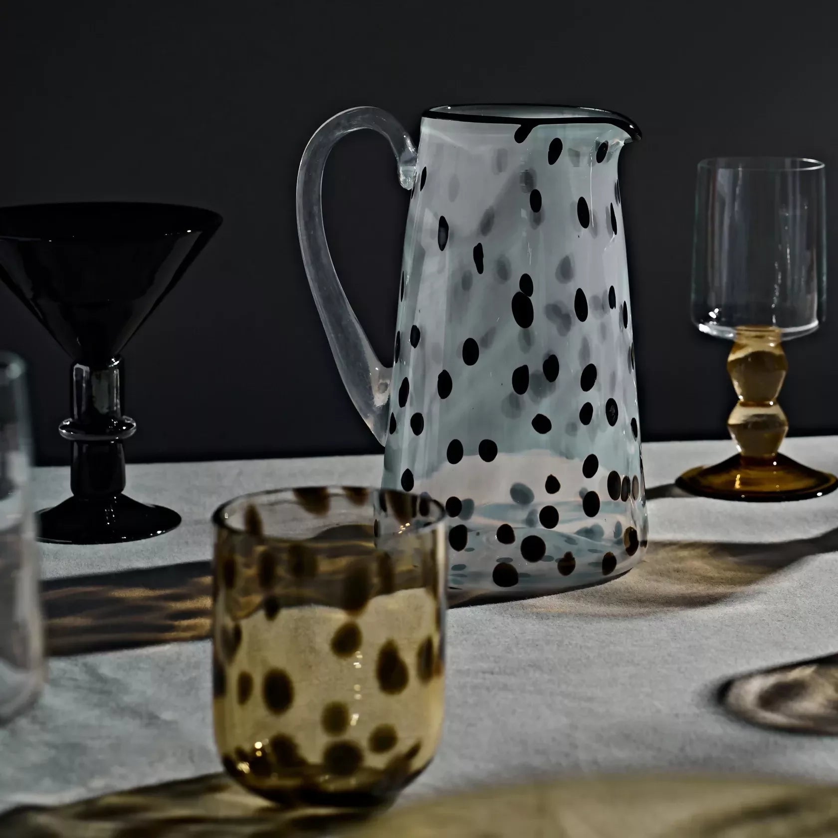 Polka dot pitcher and glassware on a table with a dark background- available  to buy on the-salon.com. SALON curates the finest , unique, handmade pieces from the interior industry's best makers and brands. Shop luxury furniture, lighting, rugs, art, antiques and vintage pieces and accessories from SALON interior designed rooms.