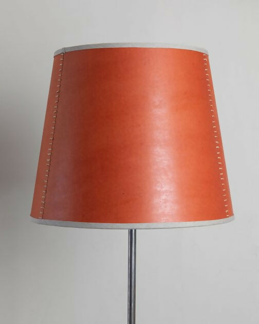 A tapered lampshade with a hand-stitched design, in Pompeian Buff colour, displayed on a stand against a neutral background, available  to buy on the-salon.com. SALON curates the finest , unique, handmade pieces from the interior industry's best makers and brands. Shop luxury furniture, lighting, rugs, art, antiques and vintage pieces and accessories from SALON interior designed rooms.
