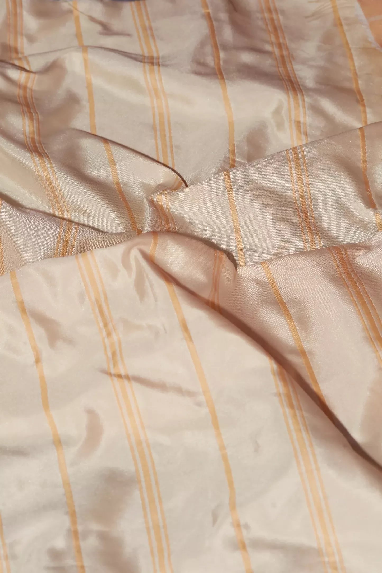 A crumpled piece of peach-colored taffeta fabric with white stripes, showcasing a smooth texture and reflective lustre,  available  to buy on the-salon.com. SALON curates the finest , unique, handmade pieces from the interior industry's best makers and brands. Shop luxury furniture, lighting, rugs, art, antiques and vintage pieces and accessories from SALON interior designed rooms.