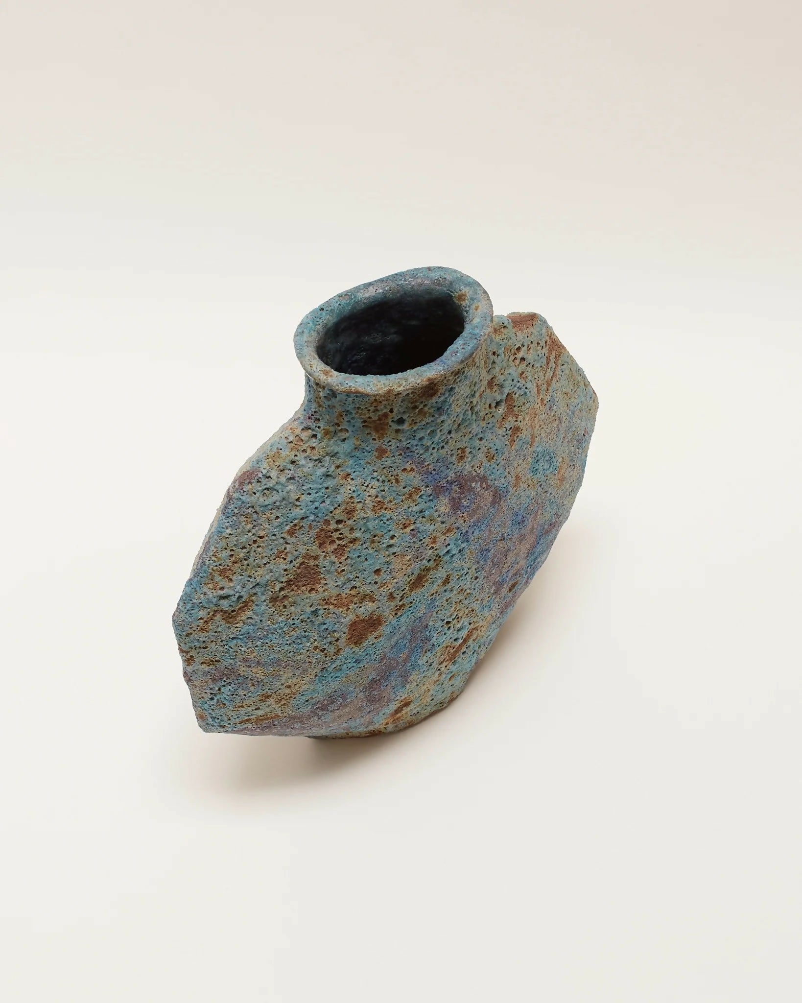 A ceramic vase with an angular form and a vibrant textural glaze in turquoise, blue, and subtle green tones,  available  to buy on the-salon.com. SALON curates the finest , unique, handmade pieces from the interior industry's best makers and brands. Shop luxury furniture, lighting, rugs, art, antiques and vintage pieces and accessories from SALON interior designed rooms.
