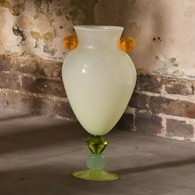 Glass vase with a green base and orange accents against a textured wall,  available  to buy on the-salon.com. SALON curates the finest , unique, handmade pieces from the interior industry's best makers and brands. Shop luxury furniture, lighting, rugs, art, antiques and vintage pieces and accessories from SALON interior designed rooms.