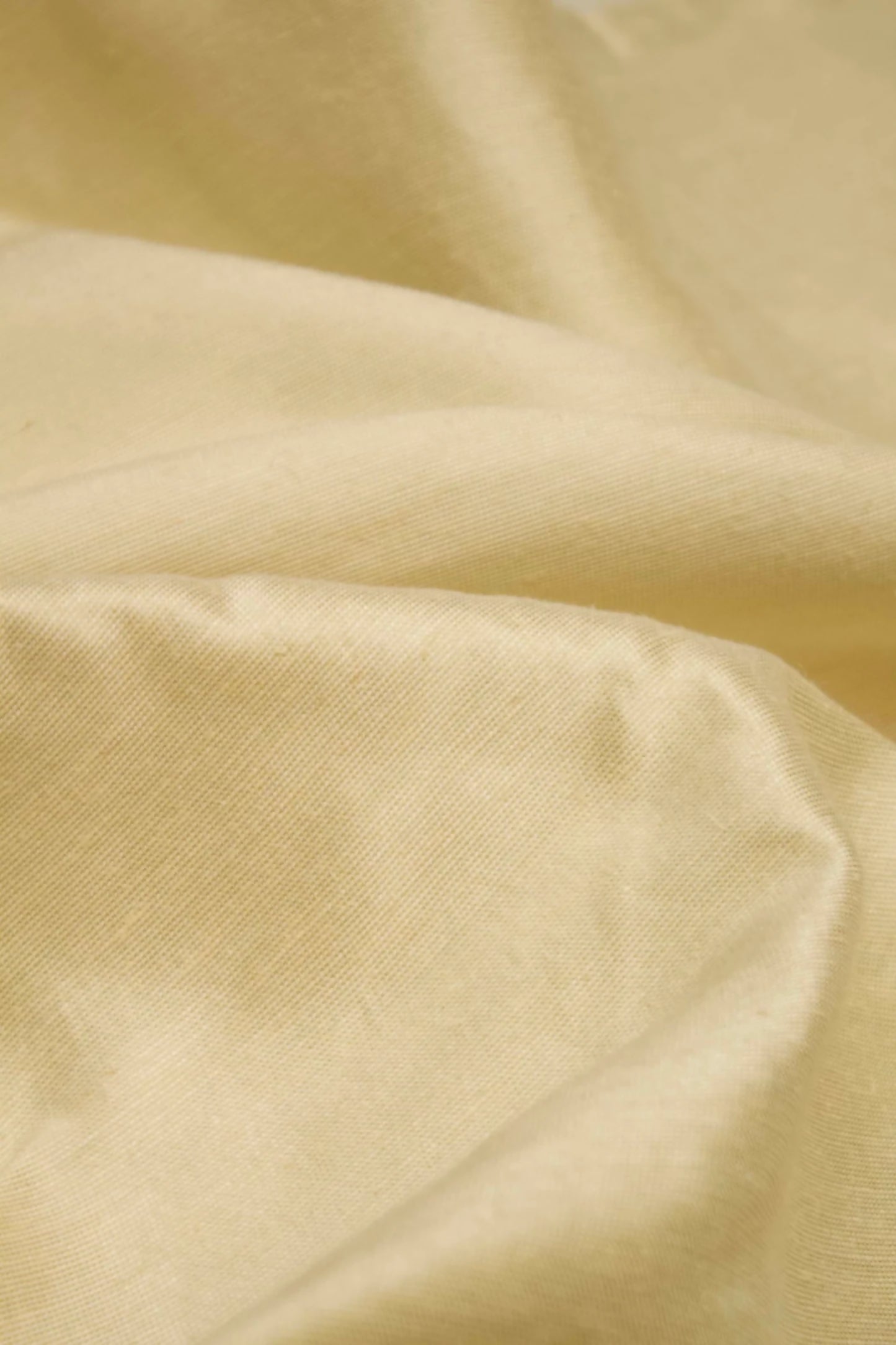Close-up of a silk sateen fabric in a pale green colour, showing the texture and sheen,  available  to buy on the-salon.com. SALON curates the finest , unique, handmade pieces from the interior industry's best makers and brands. Shop luxury furniture, lighting, rugs, art, antiques and vintage pieces and accessories from SALON interior designed rooms.