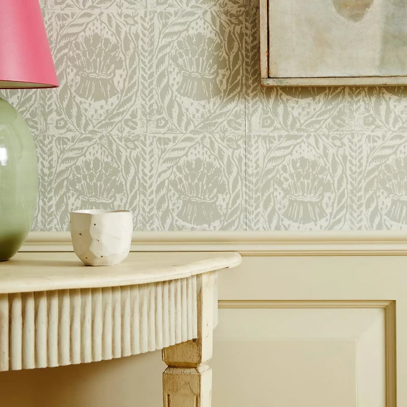 A section of wallpaper with a smoky quartz color featuring a floral and geometric pattern design on a wall with a table in the foreground,  available  to buy on the-salon.com. SALON curates the finest , unique, handmade pieces from the interior industry's best makers and brands. Shop luxury furniture, lighting, rugs, art, antiques and vintage pieces and accessories from SALON interior designed rooms.