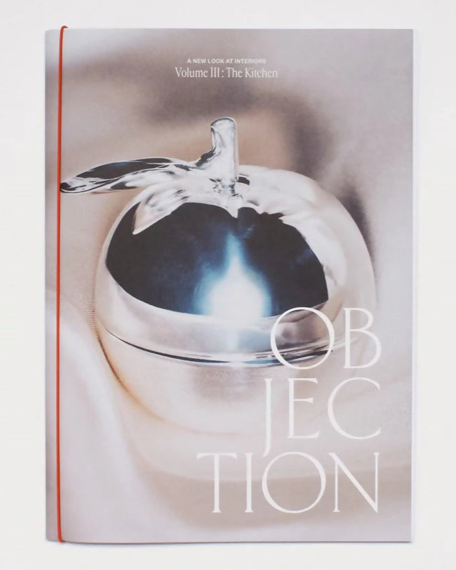 Cover of OBJECTION VOLUME III featuring a silver apple on a reflective surface with the title 'OBJECTION' printed above,  available  to buy on the-salon.com. SALON curates the finest , unique, handmade pieces from the interior industry's best makers and brands. Shop luxury furniture, lighting, rugs, art, antiques and vintage pieces and accessories from SALON interior designed rooms.