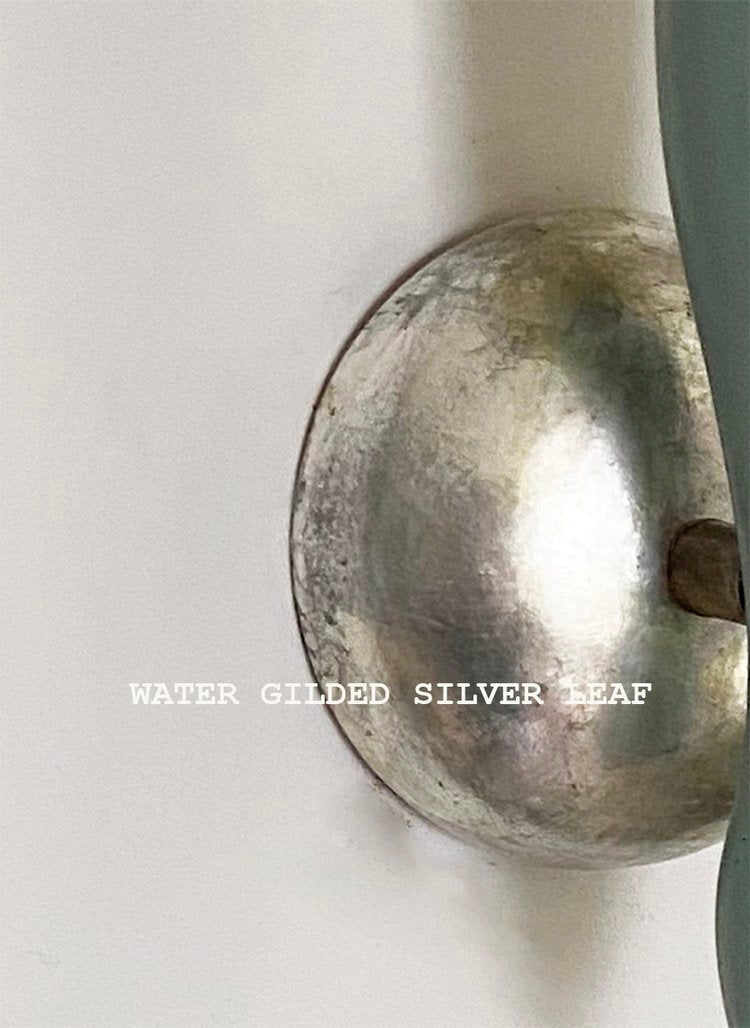 A close up on the base of the wall lamp, in silver colour,"water gilded silver leaf", available  to buy on the-salon.com. SALON curates the finest , unique, handmade pieces from the interior industry's best makers and brands. Shop luxury furniture, lighting, rugs, art, antiques and vintage pieces and accessories from SALON interior designed rooms.