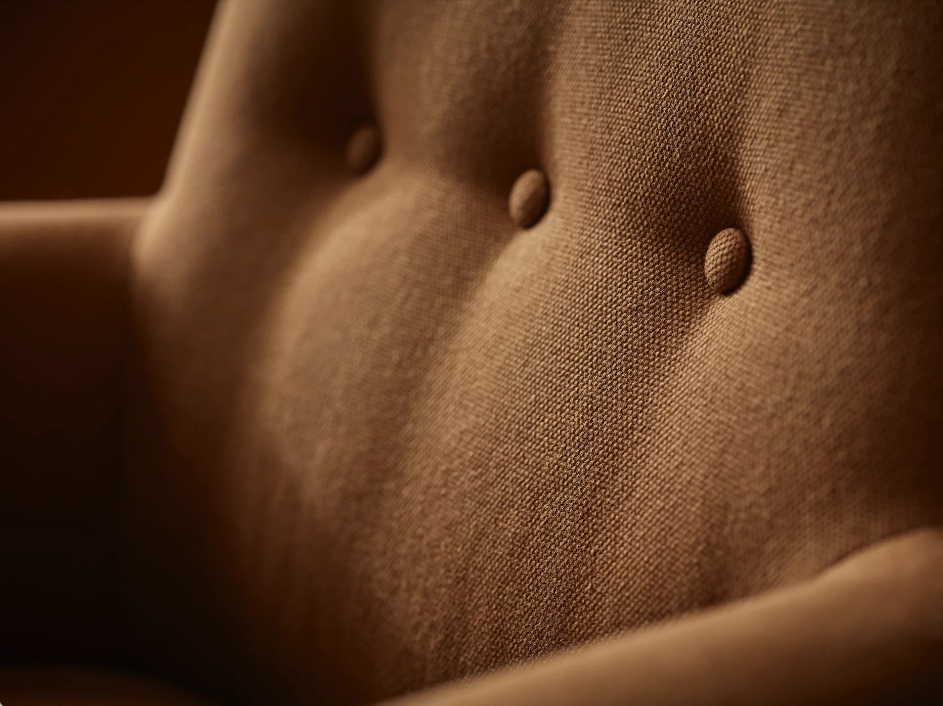A brown upholstered armchair with button back detailing and scroll arms, set against a wooden panel background,  available  to buy on the-salon.com. SALON curates the finest , unique, handmade pieces from the interior industry's best makers and brands. Shop luxury furniture, lighting, rugs, art, antiques and vintage pieces and accessories from SALON interior designed rooms.