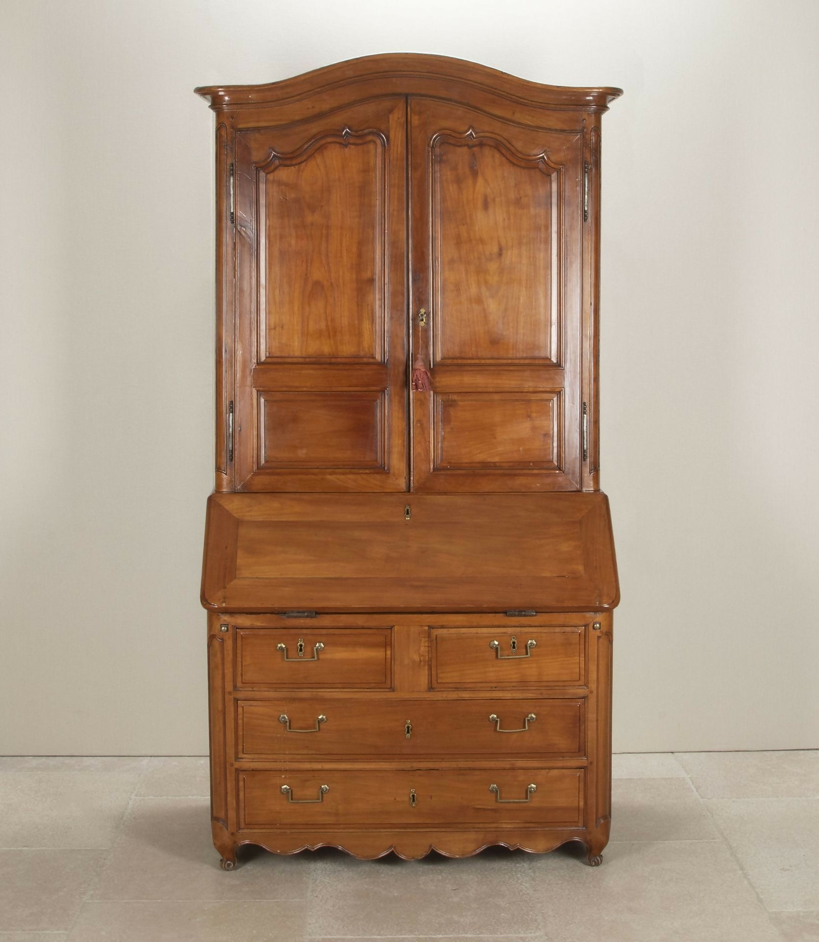 Wooden wardrobe with two doors and multiple drawers on a beige background,  available  to buy on the-salon.com. SALON curates the finest , unique, handmade pieces from the interior industry's best makers and brands. Shop luxury furniture, lighting, rugs, art, antiques and vintage pieces and accessories from SALON interior designed rooms.