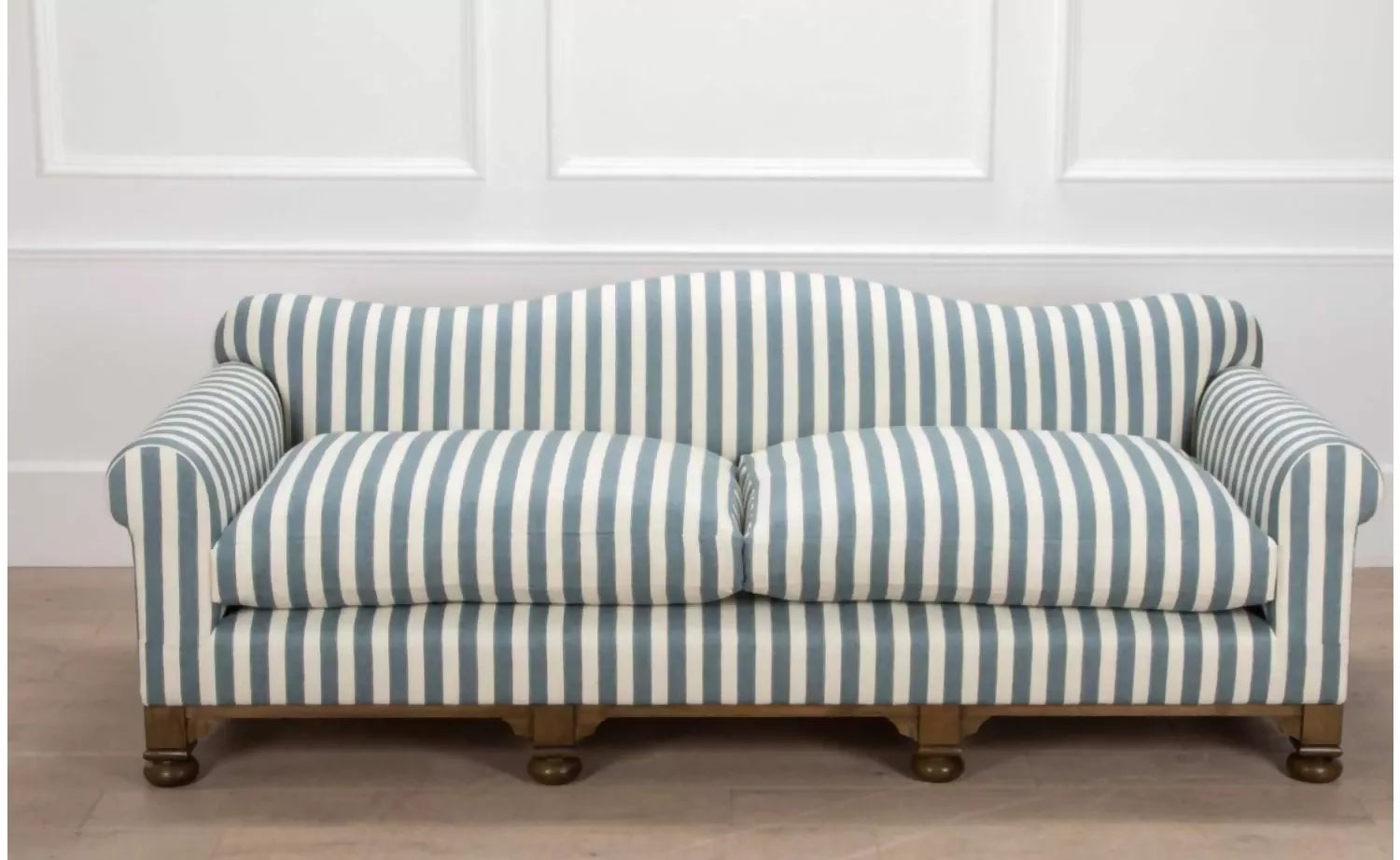A blue and white striped camel back sofa with solid oak turned legs in a room with decorative items on top, available  to buy on the-salon.com. SALON curates the finest , unique, handmade pieces from the interior industry's best makers and brands. Shop luxury furniture, lighting, rugs, art, antiques and vintage pieces and accessories from SALON interior designed rooms.