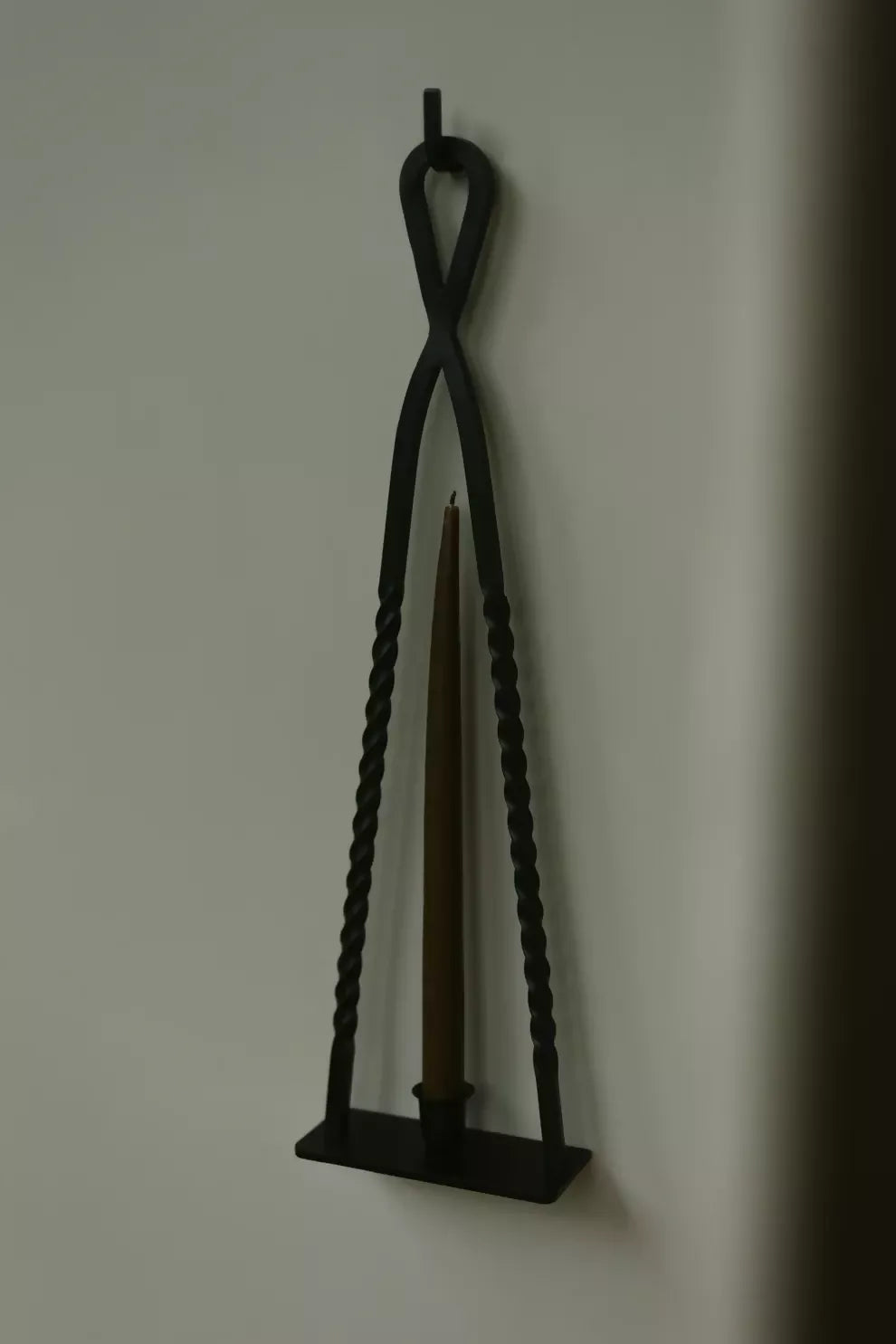 A black, handmade steel Alchemy candle holder by HUEY, displayed on a gray background with a candle inside it, available  to buy on the-salon.com. SALON curates the finest , unique, handmade pieces from the interior industry's best makers and brands. Shop luxury furniture, lighting, rugs, art, antiques and vintage pieces and accessories from SALON interior designed rooms.